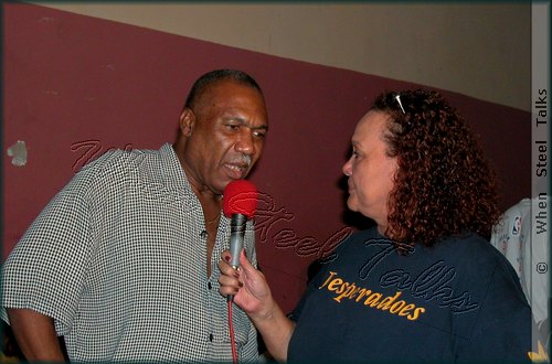 Wearing her Desperadoes 'T-Shirt', Allison Hennessy interviews Len "Boogsie" Sharpe at the 'wake' for the late Clive Bradley in Desperadoes' Panyard