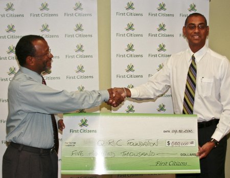 At left:  Robert Lewis - General Manager, First Citizens Bank presents Mortimer Baptiste, Committee Member (right) with a cheque