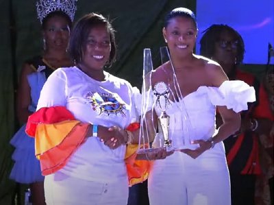Krystal Nestor (left foreground) arranger for Pantastic Muzik Steel Orchestra,receives the third-place trophy from Tamara Gibson (right)
