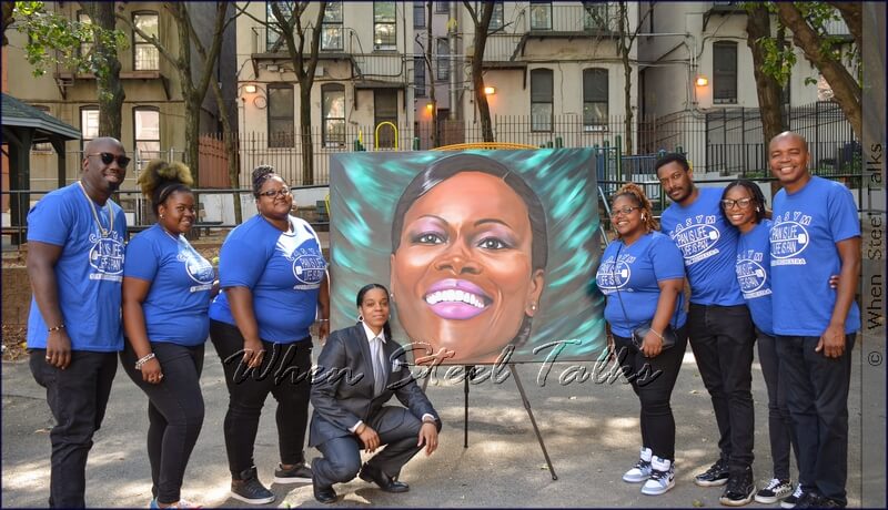 Members of CASYM Steel Orchestra’s stage side with artist J. Moses  Harper and her painting of Cicely Tyson, before the band performed