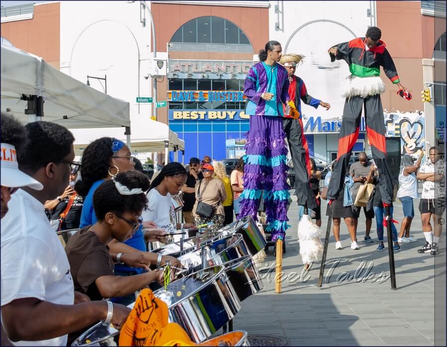 Stilt walkers aka moko jumbies show ‘how it’s done’ to the sounds of steel from Pan In Motion