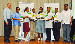 Luis Araujo, left, communications advisor, bpTT and Andre Moses, right, president, PSCC, share the spotlight with the top performers of the bpTT-sponsored music workshops held during the July-August vacation. 