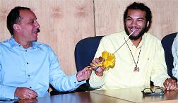Managing director of West Indies Tobacco Company Jean-Pierre du Coudray, left, presents new Witco Desperadoes arranger Andre White with a gift-wrapped baton during a news conference to introduce White this week