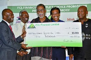 Neal and Massy All Stars manager Beresford Hunte, centre, is very delighted as he receives a $10,000 cheque from Daniel Lambert, left, on behalf of his band for winning the Peoples Choice award in the large band category of the recent Panorama finals. Also in picture are Richard Forteau, second from left, Bryon Serrette, second from right, and Keith Diaz