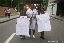 PEACE WALK: A mother and her two children who carry placards talking about peace and harmony, participate in Pan Trinbago's Peace Walk on Abercromby Street yesterday