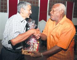 Reggie Ramnath, left, accountant at Joseph Charles Bottling Works, maker of Solo Beverages, makes a presentation to Harmonites captain Shelford Lawrence.