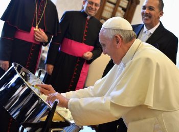 Pope Francis plays a tenor pan received as a gift by former President of Trinidad and Tobago, George Maxwell Richards (unseen) during a private audience at the Vatican July 6, 2013.  REUTERS/Gabriel Bouys-Pool
