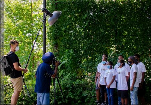 Members of CrossFire Steel Orchestra work with photographer Wayne Lawrence (center) during the National Geographic photoshoot at the Harry Maze Playground in Brooklyn