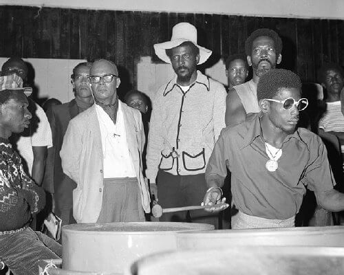 Prime Minister Dr. Eric Williams takes in a practice session at the Desperadoes panyard with leader Rudolph Charles at his side