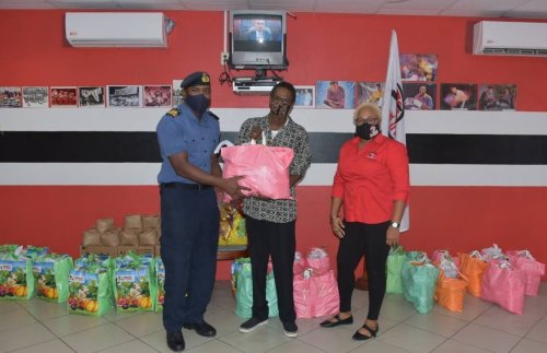 Lieut Sherron Manswell of TT Defence Force, left, presents a hamper to Anthony Kinsale from Laventille Serenaders Steel Orchestra, while Northern Region Pan Trinbago chairman Desiree Myers looks on