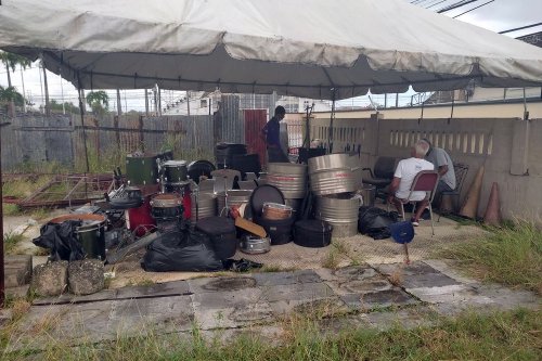 Woodbrook Playboyz members wait to be remove instruments under a tent after they were evicted from their Fitzblackman Drive, Woodbrook panyard on Wednesday