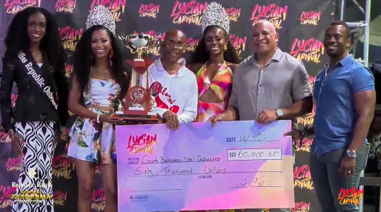 Babonneau Steel Orchestra’s champion arranger Allison Marquis, in white, wearing glasses - presented with trophy and check for his band